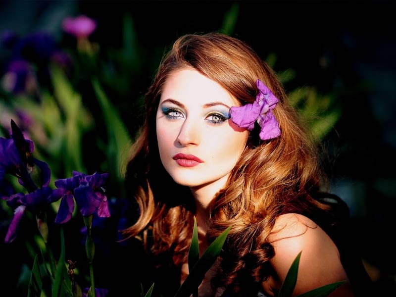 A beautiful woman standing near blue flowers A beautiful woman standing near blue flowers