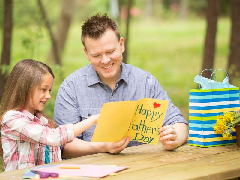 A sweet girl showing Father's Day greeting card to her Father A sweet girl showing Father's Day greeting card to her Father